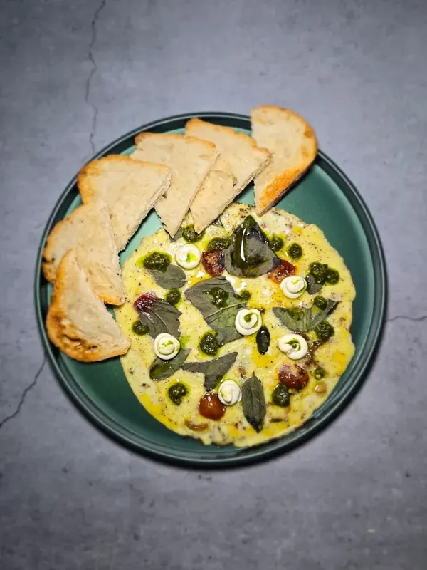 Egg breakfast dish on a green plate with freshly baked sourdough toast at Moi Doughssier